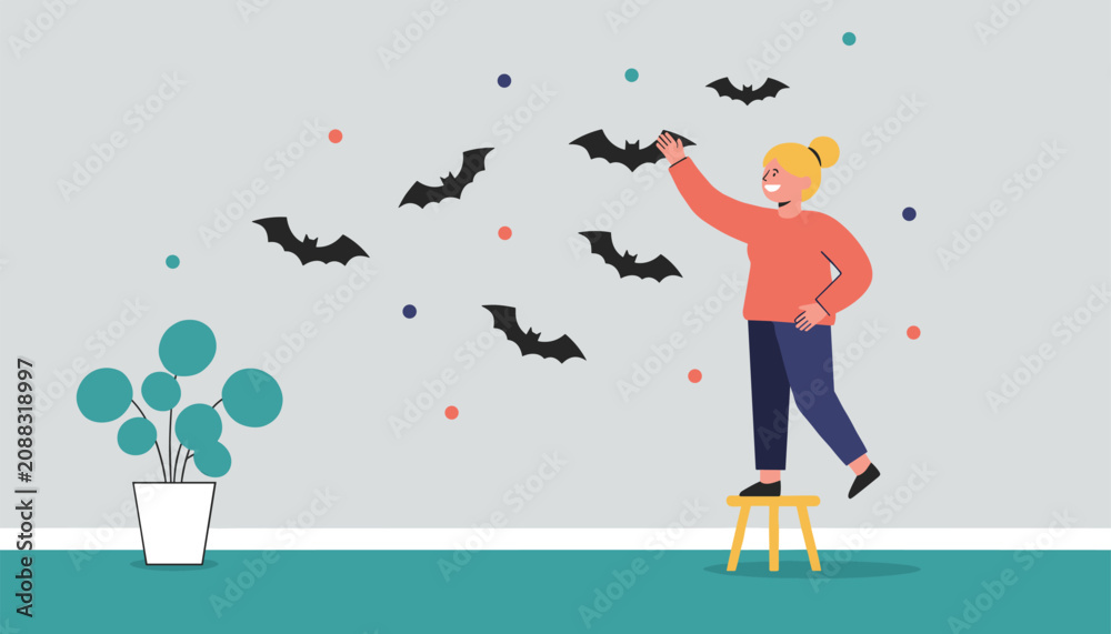 Naklejka premium Young woman stands on a wooden stool to put up flying bat stickers on her room wall as part of Halloween decor.