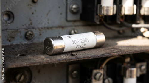 Old Industrial 10A 250V Electrical Ceramic Fuse Lying on Metal Panel Shelf