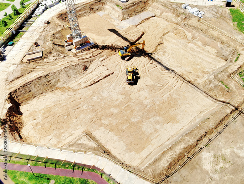 Aerial View Construction Site With Excavator and Crane Shadow Preparing Foundation and Earthworks