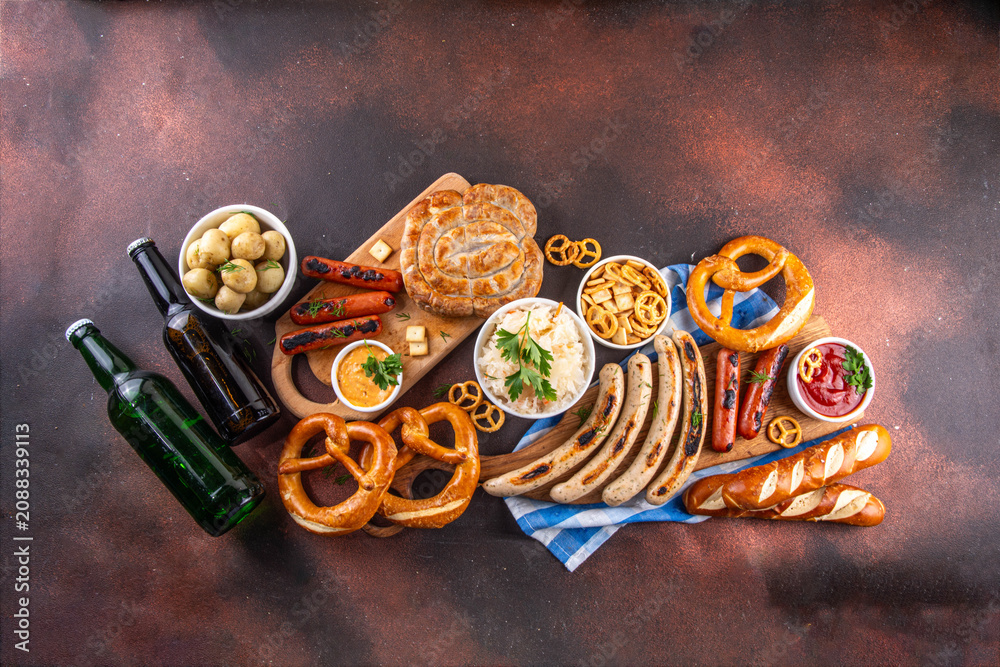 Fototapeta premium Oktoberfest picnic and barbecue food, bavarian party menu, bavarian sausages, pretzels, potato, sauerkraut, beer bottles, with picnic basket, checkered napkin tablecloth, Oktoberfest festive ribbon