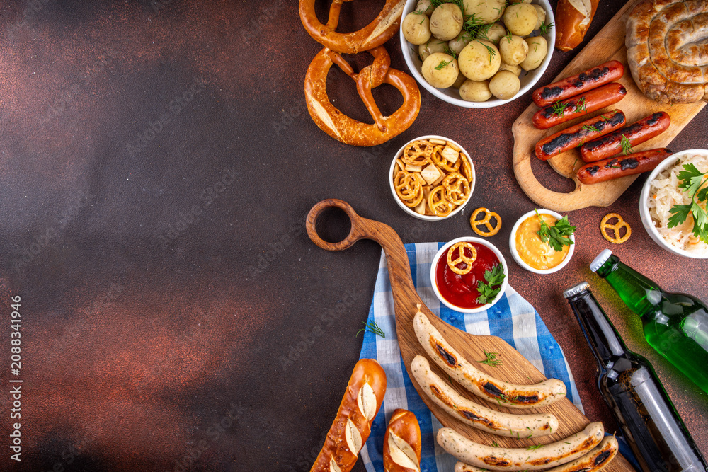 Fototapeta premium Oktoberfest picnic and barbecue food, bavarian party menu, bavarian sausages, pretzels, potato, sauerkraut, beer bottles, with picnic basket, checkered napkin tablecloth, Oktoberfest festive ribbon
