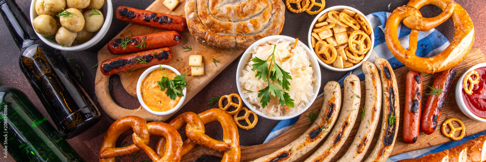Fototapeta premium Oktoberfest picnic and barbecue food, bavarian party menu, bavarian sausages, pretzels, potato, sauerkraut, beer bottles, with picnic basket, checkered napkin tablecloth, Oktoberfest festive ribbon