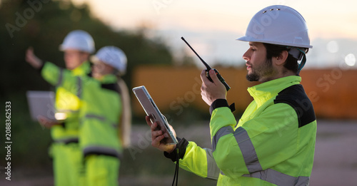 Foto Construction workers collaborating on site with communication devices in high vi