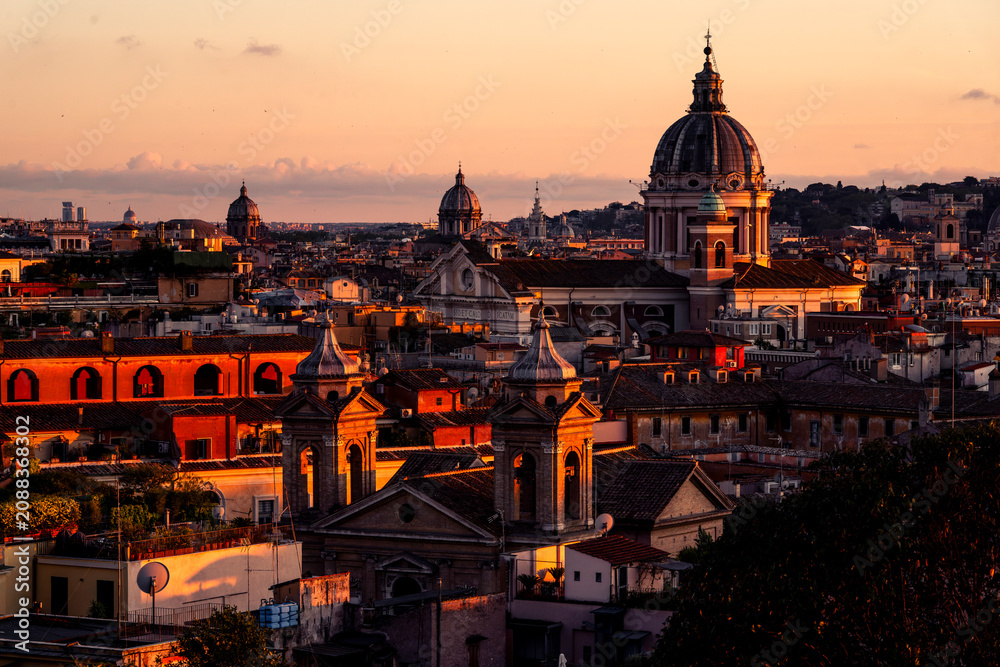 Fototapeta premium Historic European city skyline with domes and terracotta rooftops bathed in golden sunset light over classical Baroque architecture