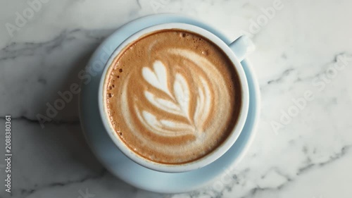 Fresh cup of cappuccino with beautiful latte art on wooden table, styled in soft pastel light blue tones creating cozy, serene and modern aesthetic.