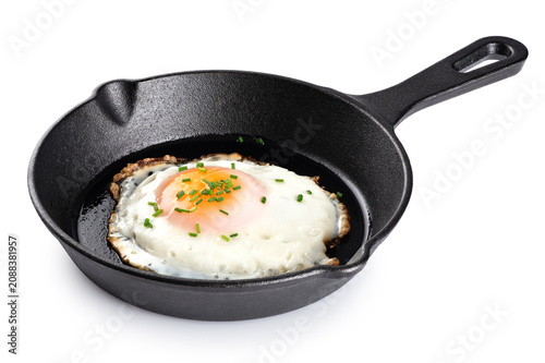 Fried egg with green onions on a cast iron mini frying pan isolated on a white background. With clipping path.