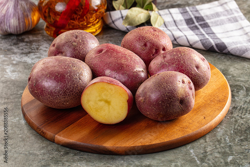 Foto Red potatoes on wooden cutting board with garlic and oil