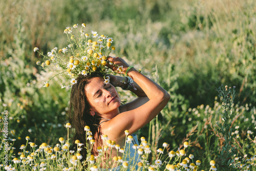 Woman with chamomile flower crown in meadow