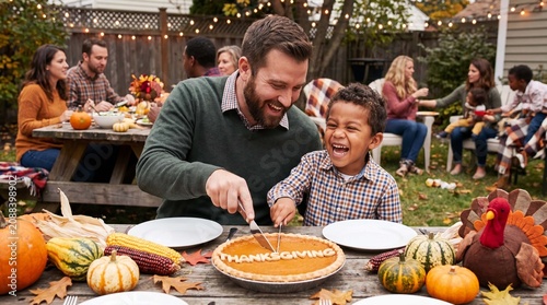 Father and son cut pumpkin pie at backyard Thanksgiving picnic for family greeting cards