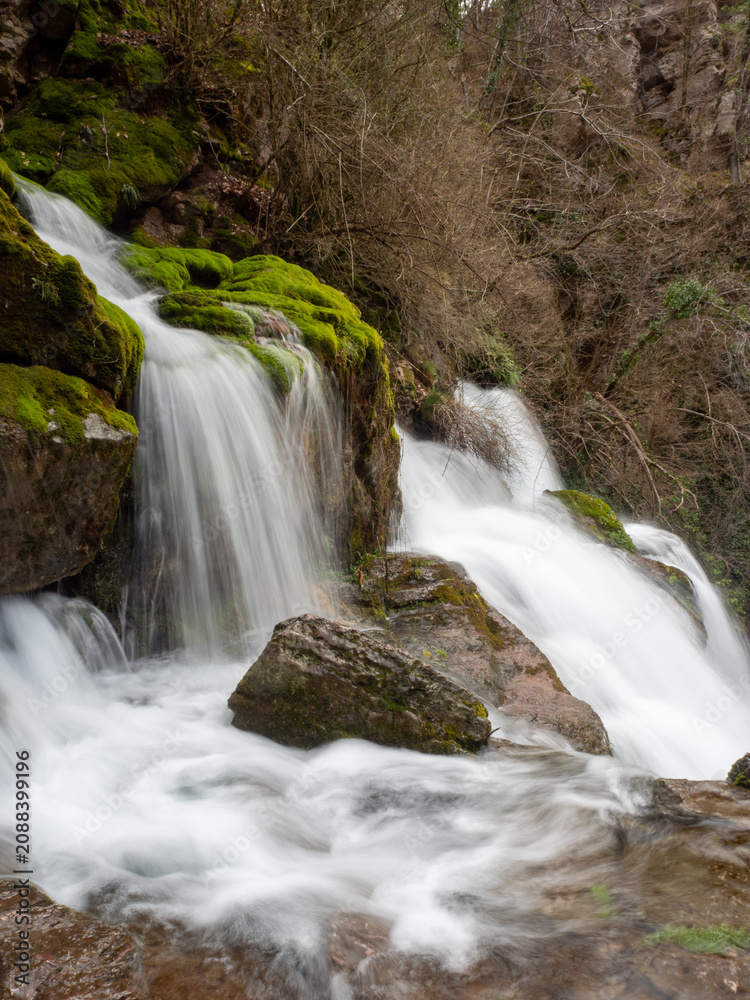 Obraz premium Beautiful waterfall cascading over mossy rocks in a lush spring forest
