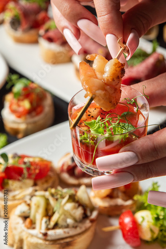 Foto A person holding a glass of shrimp cocktail shooter appetizer at a catering party event