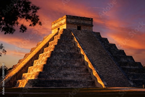 El Castillo pyramid at Chichen Itza during sunset with vibrant orange and pink sky
