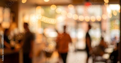 A blurred image of a cafe interior with warm lights and indistinct figures. The soft bokeh effect creates a cozy and inviting atmosphere.