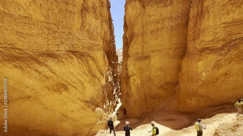 A smooth cinematic video of tourists exploring a narrow valley of towering red rock spires in Bryce Canyon, Utah. Bright sunny day, unforgettable travel and adventure atmosphere. Lifestyle concept.