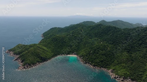 A tranquil bay with crystal clear turquoise waters and lush green hills. Koh Tao, Thailand.