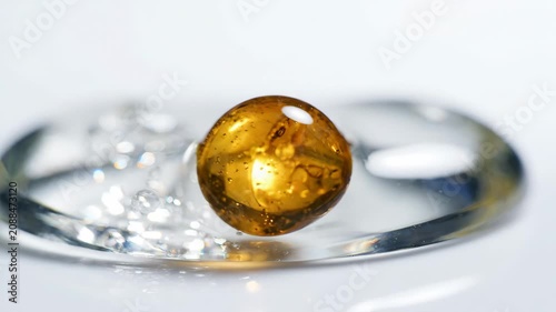 Golden oil drop clear gel surface with smooth texture and light reflection amber sphere bubbles close up macro photography