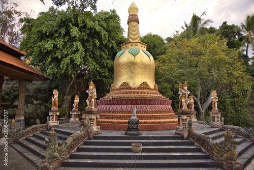 Foto A magnificent golden stupa pagoda structure surrounded by stone guardian statues and dragon steps under a cloudy sky at the Brahma Vihara Arama buddhist monastery in Bali, Indonesia