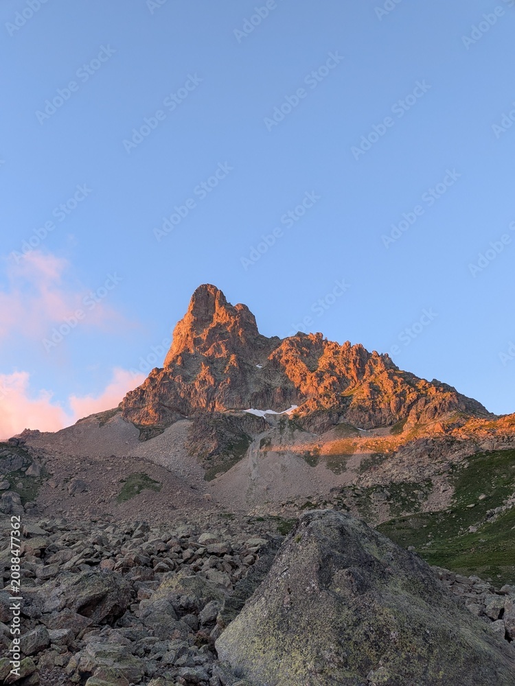 Naklejka premium Golden sunset light illuminating the peak of Pic du Midi d'Ossau in the Pyrenees mountains, scenic alpine landscape at dusk