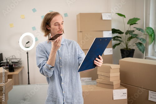 Foto Starting an SME, male small business entrepreneur using smartphone packaging box in online store