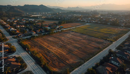 Aerial drone view of empty residential land divided into lots with clear boundary lines, concrete roads, green landscape, mountain background, land development project, Thailand style suburban area, u