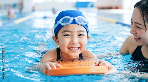 Naklejka スイミングスクールでコーチから水泳を教わる小学生の子ども