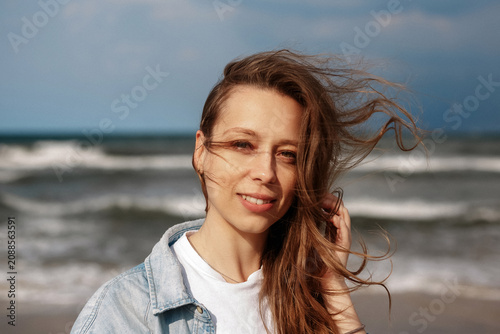 Принти на полотні Portrait of a smiling woman on a beach with windblown hair, capture of authentic
