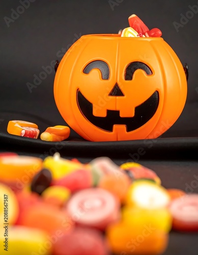 Bright Plastic Jack O Lantern Candy Bucket on Dark Halloween Table