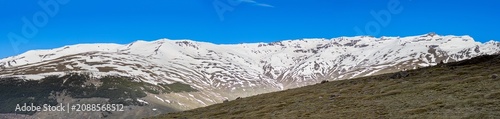 Panoramic view of the snow capped peaks of the Sierra Nevada Mountains revealing dramatic alpine landscapes and winter light in Spain