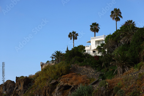 фотографія modern hillside house with white multi level terraces positioned above rocky slo