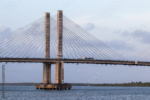 Cable-stayed bridge over a river with vehicle traffic and an evening sky.