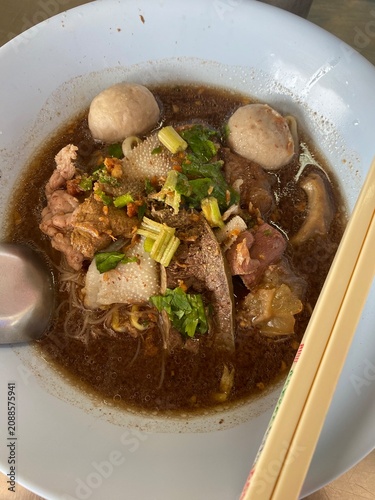 Beef noodle soup. Thai noodle soup. Thai food. Asian food. Braised beef. Beef meatballs. Noodles. Hot broth. Chopsticks. Homemade food. Bowl of noodles. Comfort food.