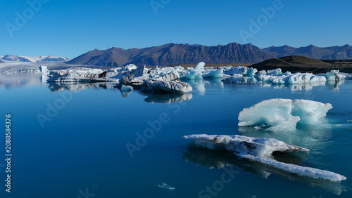 Foto Floating blue icebergs in a calm glacial lagoon under clear skies in Iceland wit