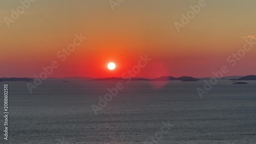 Sunset over the ocean with distant islands in view as the sky changes colors during the evening in a beautiful coastal location