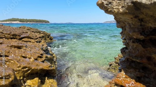 Explore clear water between rocks at a beach in summer sunlight near an island in Croatia