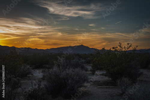 Canvastavla Scenic desert landscape at twilight with dark mountain silhouettes under a vibrant warm dusk sky