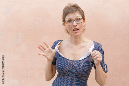 Fotografie Worried woman raising hands with uneasy expression against pastel wall