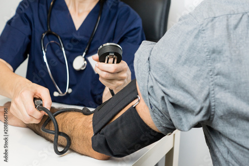 Fotografía Clinical professional inflating a blood pressure cuff and checking the diagnostic manometer gauge during a cardiovascular wellness screening