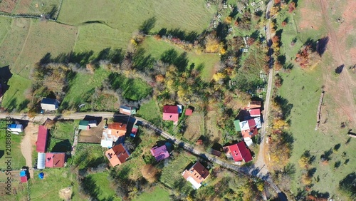Colorful rooftops of a Mengen village scattered amid green pastures and autumn trees, overhead aerial view. Bolu, Turkey. Aerial view, drone shot