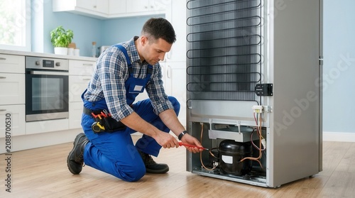 Service worker performing maintenance on a refrigerator appliance in a kitchen.