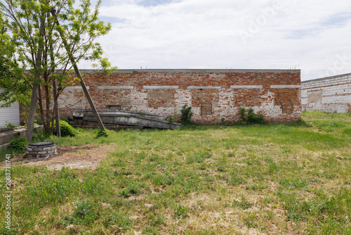 Unfinished abandoned brick building in an overgrown yard