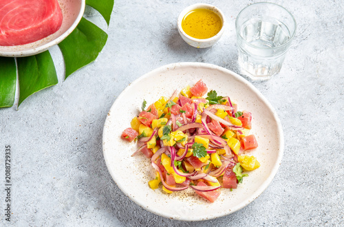 Tropical Hawaiian tahitian tuna mango salad on white plate on tropical monstera leafe
