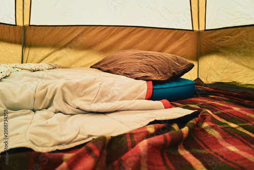 Cozy tent interior with sleeping bag and plaid blanket