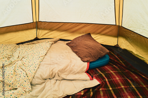 Inside a camping tent - sleeping bag and bedding laid out