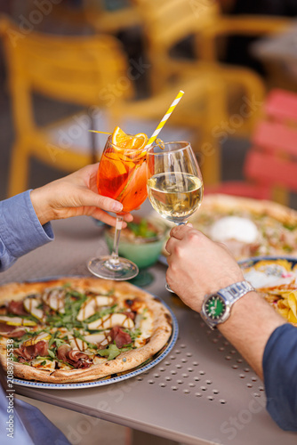 Friends toasting with cocktails and wine over pizza
People celebrating with drinks in Italian restaurant
Cheers with Aperol Spritz and wine during dinner