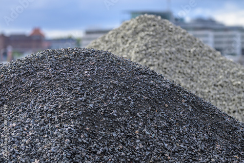 Dark gravel piles at urban construction site with skyline.