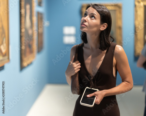 Fotografía Woman of European appearance visits an exhibition of paintings in a museum, she