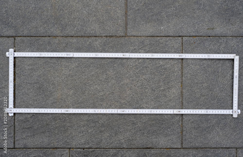 Fototapeta premium White Folding Ruler Formed into a Rectangle Shape, Lying on Patio Paving Slabs, Construction Measurement and Geometric Layout Concept