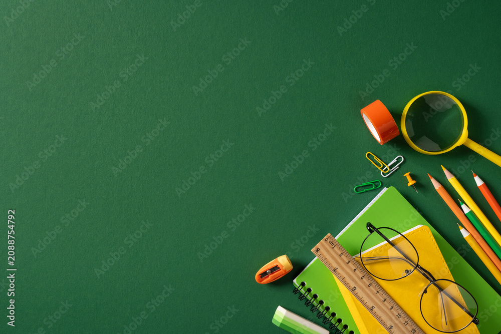 Obraz premium Back to school flat lay with green and yellow stationery, pencil, notebook, ruler and glasses