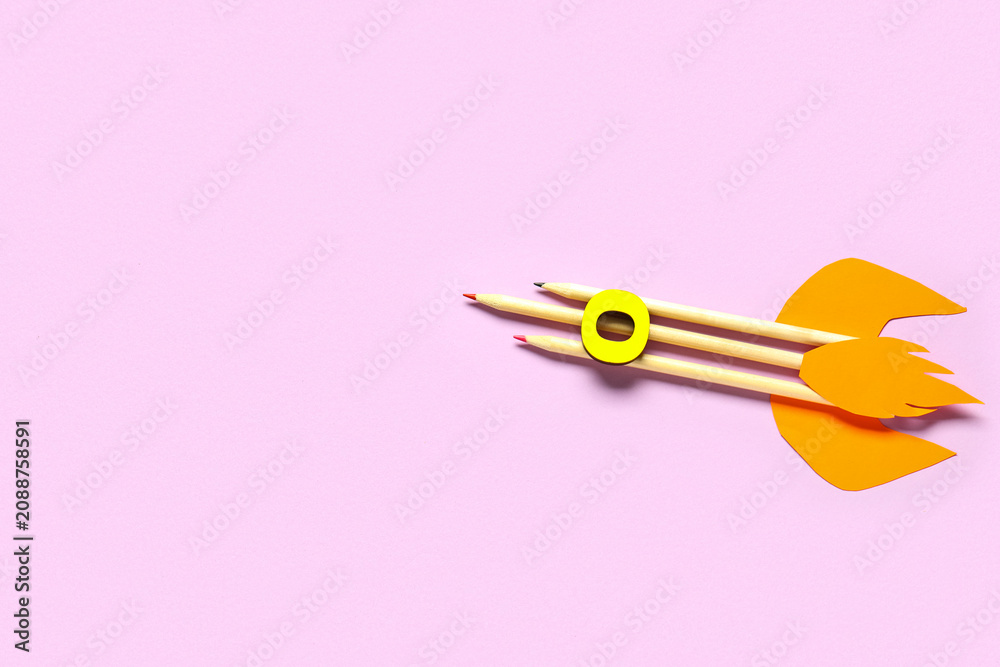 Fototapeta premium Rocket made of pencils, paper and wooden letter on pink background