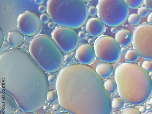 Macro video of iridescent spheres floating freely in water.